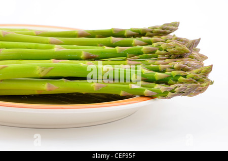 Frischen rohen Spargel auf rustikale Platte isoliert auf weißem Hintergrund mit Textfreiraum Stockfoto