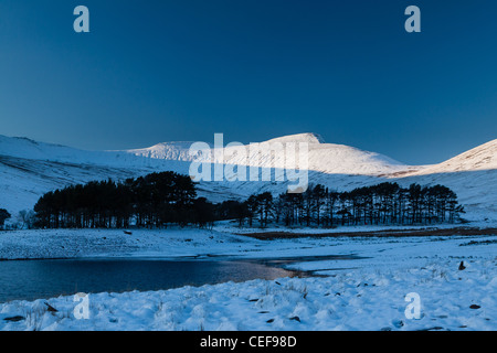 Der Gipfel des Schnees begrenzt Berge durch die späte Nachmittagssonne beleuchtet, während einen gefrorenen See und Schnee im tiefen Schatten liegen. Stockfoto