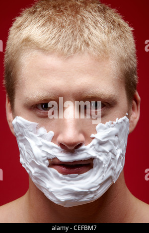 Junger Mann mit Schaum auf seinem Gesicht zu rasieren Stockfoto