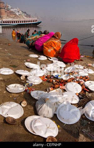 Indien, Uttar Pradesh, Varanasi, Assi Ghat, hell gekleidet Pilger von Müll Haufen neben Fluss Ganges Stockfoto