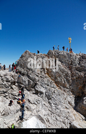 Touristen klettern Zum Goldenen Kreuz - der höchste Punkt in Deutschland auf dem Gipfel der Zugspitze mit 2962 m über dem Meeresspiegel Stockfoto