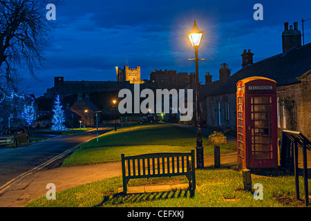 Bamburgh Dorf, Northumberland, England, UK, in der Abenddämmerung mit Bamburgh Castle im Hintergrund, zu Weihnachten Stockfoto