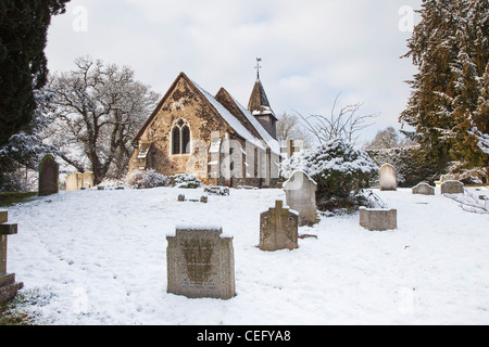 St.-Nikolaus Kirche, Church Hill, Pyrford, Surrey, England mit Grab Grabsteine und Kreuze auf Friedhof im Schnee Stockfoto