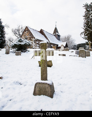 St.-Nikolaus Kirche, Church Hill, Pyrford, Surrey, England mit Grab Grabsteine und Kreuze auf Friedhof im Schnee Stockfoto