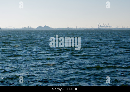 Blick auf New Yorks Upper Bay von Red Hook, Brooklyn nach Bayonne, New Jersey, Krane Schiffe und Schifffahrt in der Ferne. Stockfoto