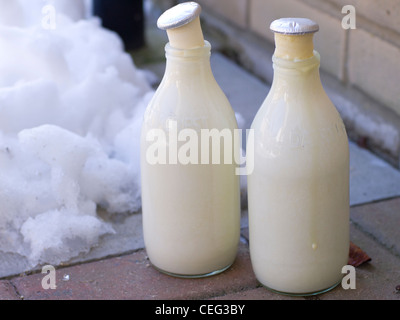 Zwei Flaschen Milch, auf eine Tür im Winter gefroren. Stockfoto