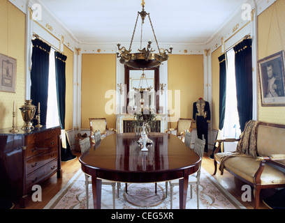 Reich verzierte Licht über antike Mahagoni-Tisch in opulenten Land Speisesaal mit Schaufensterpuppe in antiken Kleidung in der Ecke des Raumes Stockfoto
