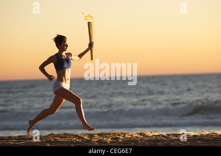 Eine Frau am Strand mit einer simulierten Olympische Relais Fackel ausgeführt. Stockfoto