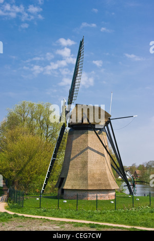 Holländische Mühle in Stadt mit Wohnhäusern im Hintergrund am April Nachmittag Stockfoto