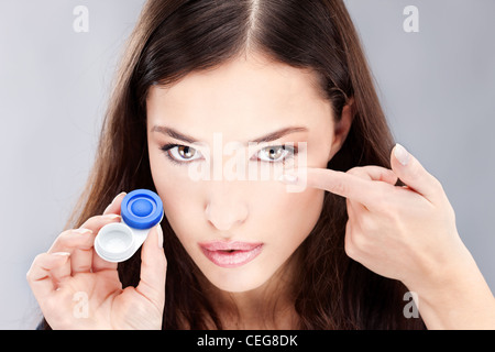 Junge Frau mit Kontaktlinsen Gehäuse und Objektiv vor ihr Gesicht Stockfoto