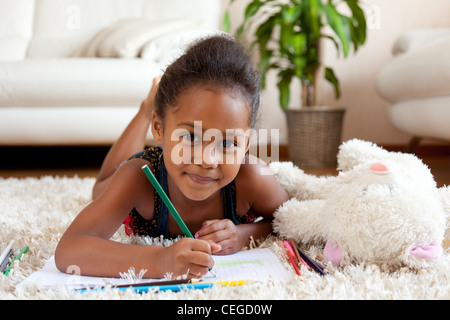 Kleine afrikanische Asiatin zeichnen, auf dem Boden liegend Stockfoto