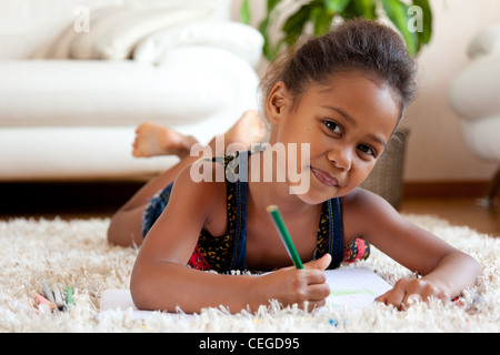 Kleine afrikanische Asiatin zeichnen, auf dem Boden liegend Stockfoto