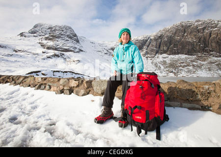 Frau Hill Wanderer durch eine gefrorene scheut Tarn in die saisonabhängige, Lake District, Großbritannien Stockfoto