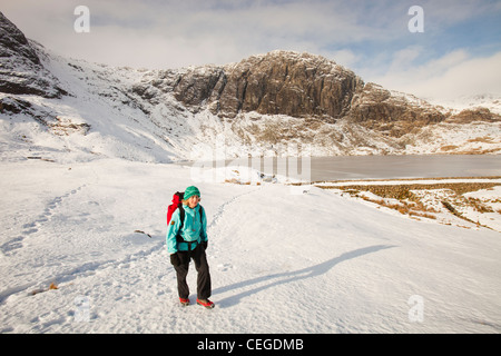 Frau Hill Wanderer durch eine gefrorene scheut Tarn in die saisonabhängige, Lake District, Großbritannien Stockfoto