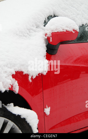 Nahaufnahme von Spiegel und vorderen Seitenrad rotes Auto mit Schnee bedeckt. Aus niedrigen Winkel aufgenommen. Stockfoto