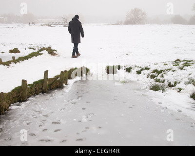 Ein Mann im Schnee in eine eisige Winterlandschaft wandern. Stockfoto