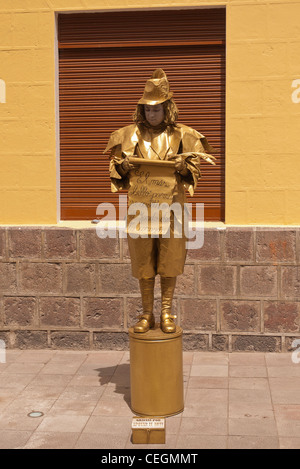 Ein 20 Jahre alten männlichen MIME-Straßenkünstler in gold Körperfarbe und gold Kleidung führt in Latacunga, Ecuador. Stockfoto