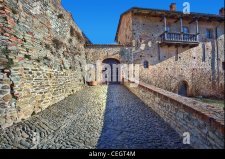 Schmale Stein gepflasterter Straße unter alten Mauer und altes Haus in der Stadt von Serralunga D'Alba, Norditalien. Stockfoto