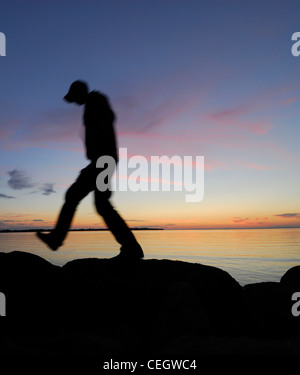 Silhouette der Mann zu Fuß an einem See in der Nacht Stockfoto