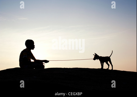 Silhouette des jungen sitzen und spielen mit seinen Welpen. Indien Stockfoto