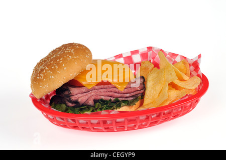 Sandwich mit Roastbeef, Salat, Tomate, Salat und geschmolzenem Käse auf Sesam Brötchen in rot Retro Korb mit Pommes frites oder Chips auf Weiß Stockfoto