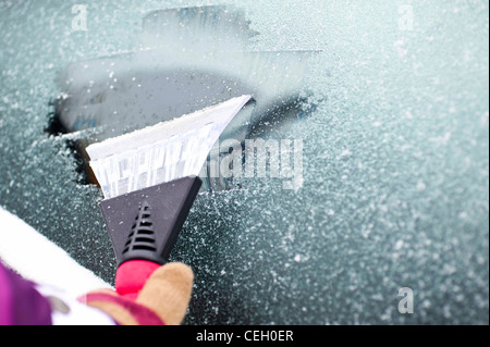 Schnee und Eis von der Auto-Windschutzscheibe kratzen Stockfoto