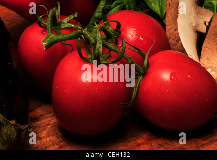 Portabella Pilze, Reben gereifte Tomaten und frischem Basilikum auf ein Schneidebrett. Stockfoto