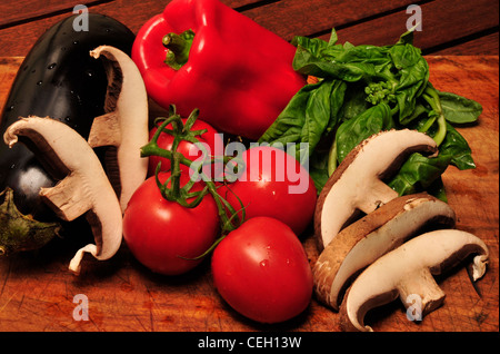 Portabella Pilze, Reben gereifte Tomaten, frischem Basilikum und Auberginen auf ein Schneidebrett. Stockfoto