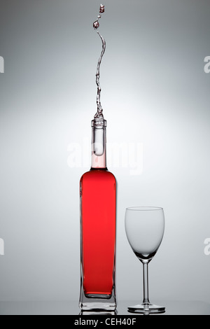 Flüssigkeit spritzt aus einer Glasflasche Stockfoto