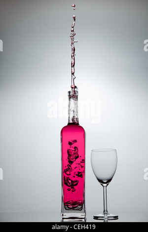 Flüssigkeit spritzt aus einer Glasflasche Stockfoto