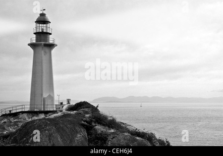 Leuchtturm mit Suchscheinwerfer - schwarz / weiß Foto von Ocean Shore mit klassischen Leuchtturm Stockfoto