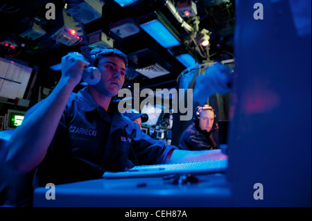 Der Operations Specialist Seaman Jacob Czarnecki übergibt eine Nachricht an den taktischen Action Officer an Bord des geführten Rakete-Kreuzer der Ticonderoga-Klasse USS Cape St. George. Cape St. George wird als Teil der Abraham Lincoln Carrier Strike Group in das US-amerikanische 5. Flottengebiet eingesetzt, das maritime Sicherheitsoperationen, Sicherheitskooperationen und Unterstützungsmissionen im Rahmen der Operation Enduring Freedom durchführt. Stockfoto