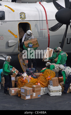 Seeleute an Bord des Nimitz-Klasse Flugzeugträgers USS Abraham Lincoln laden Post auf einen C-2A Greyhound, der den Anbietern von Carrier Logistics Support Squadron (VRC) 30 zugewiesen wurde. Abraham Lincoln wird in den Zuständigkeitsbereich der 5. US-Flotte eingesetzt, um maritime Sicherheitsoperationen durchzuführen, Sicherheitskooperationen zu betreiben und Unterstützungsmissionen im Rahmen der Operation Enduring Freedom durchzuführen. Stockfoto