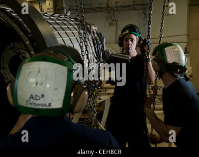 Aviation Machinist's Mate 3. Klasse Ryan Thomas, Aviation Machinist's Mate 3. Klasse David Blount und Airman Travis Baldridge, alle zugeordnet zu den Flugzeugen Zwischenwartung Abteilung an Bord der Nimitz-Klasse Flugzeugträger USS Carl Vinson, bewegen ein Kompressor-Modul für einen F404 Turbofan. Carl Vinson und Carrier Air Wing (CVW) 17 werden im Verantwortungsbereich der 5. US-Flotte eingesetzt. Stockfoto