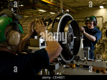 Airman Travis Baldridge und Aviation Machinist's Mate 3. Klasse Ryan Thomas, beide an Bord des Nimitz-Klasse Flugzeugträgers USS Carl Vinson der Flugzeugzwischenwartung zugeordnet, sichern ein Kompressormodul für einen F404 Turbofan. Carl Vinson und Carrier Air Wing (CVW) 17 werden im Verantwortungsbereich der 5. US-Flotte eingesetzt. Stockfoto