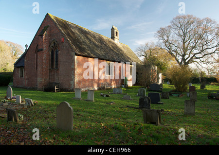 Der seltsame kleine rote Ziegel Mariä Himmelfahrt und der Friedhof, in Dorset Dorf von Waldgebieten. England, United Kingdom. Stockfoto