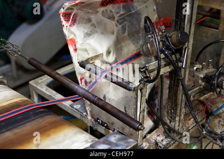 Fahrrad Reifen Gummi wird durch eine Maschine in der Hutchinson-Reifenfabrik abgeflacht Streifen Stockfoto