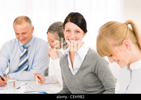 Geschäftsfrau, die lächelnd an Team-Meeting mit Kollegen Stockfoto