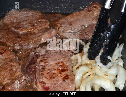 Steak und kochen in einer Pfanne anbraten Zwiebeln Stockfoto