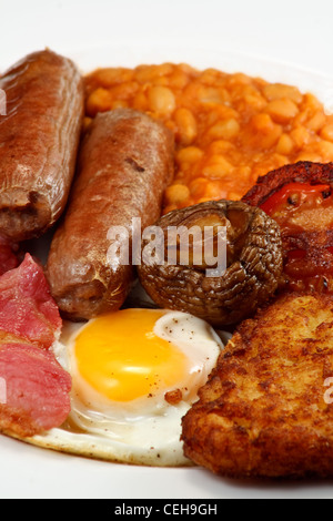 Typisch englisches Frühstück bestehend aus Wurst, Speck, Ei, Champignons, Rösti, Bohnen und gebratene Tomaten Stockfoto