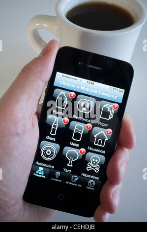 Person mit recycling app, überflüssige Elemente auf ein iPhone 4 G Smartphone recyceln zu überprüfen Stockfoto