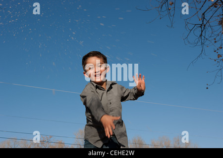 Hispanische sieben Jahre alter Junge werfen Schnee unter blauem Himmel. Stockfoto