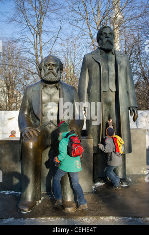 Kinder klettern auf Bronzestatuen von Marx und Engels in Alexanderplatz Mitte Berlin Deutschland Stockfoto