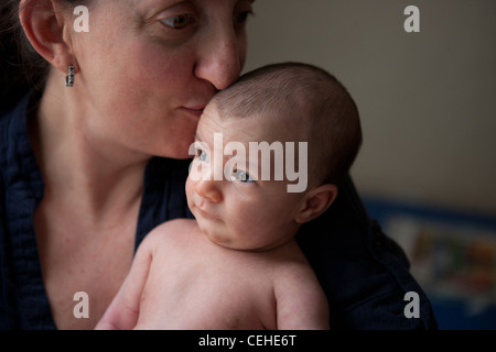 Nahaufnahme einer vierzig Jahre alten Mutter küssen ihre neugeborene Tochter. Stockfoto