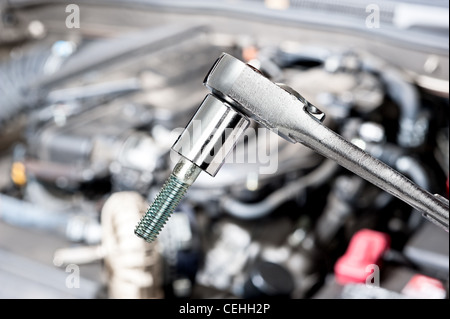 Ein glänzendes Chrom-Steckschlüssel vor einem Automotor vor für Wartung und Reparatur Stockfoto