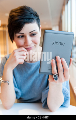 Junge Frau lesen Ebook auf eine Amazon Kindle, London, England, UK Stockfoto