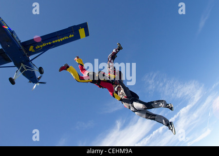 Bildung Fallschirmspringer halten einander und Sprung aus einem Flugzeug in den blauen Himmel über den Wolken. Stockfoto