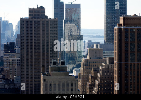 Ein Blick unter chaotischen durcheinander Manhattans Wolkenkratzer und niedrigeren Gebäuden, mit Ellis Island in der Ferne. Stockfoto