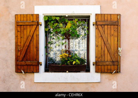 Ein hübsches Fenster in einem französischen Dorf, mit Blumen und Fensterläden aus Holz. Stockfoto