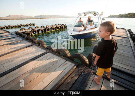 Junge stand an einem Anlegesteg mit Boot im Hintergrund, Hartebeestpoort Dam, North West Province Stockfoto